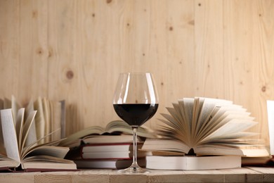 Photo of Glass of red wine and open books on wooden table. Space for text