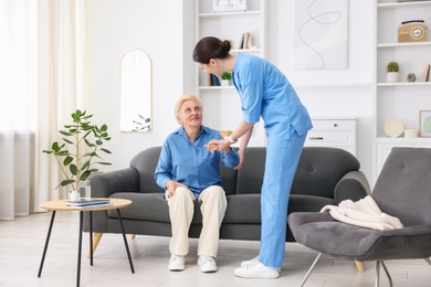 Photo of Nurse assisting senior woman indoors. Home health care service