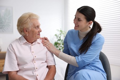 Photo of Nurse assisting senior woman indoors. Home health care service