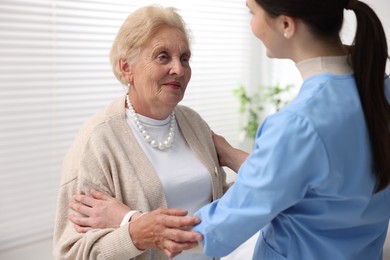 Photo of Nurse assisting senior woman indoors. Home health care service