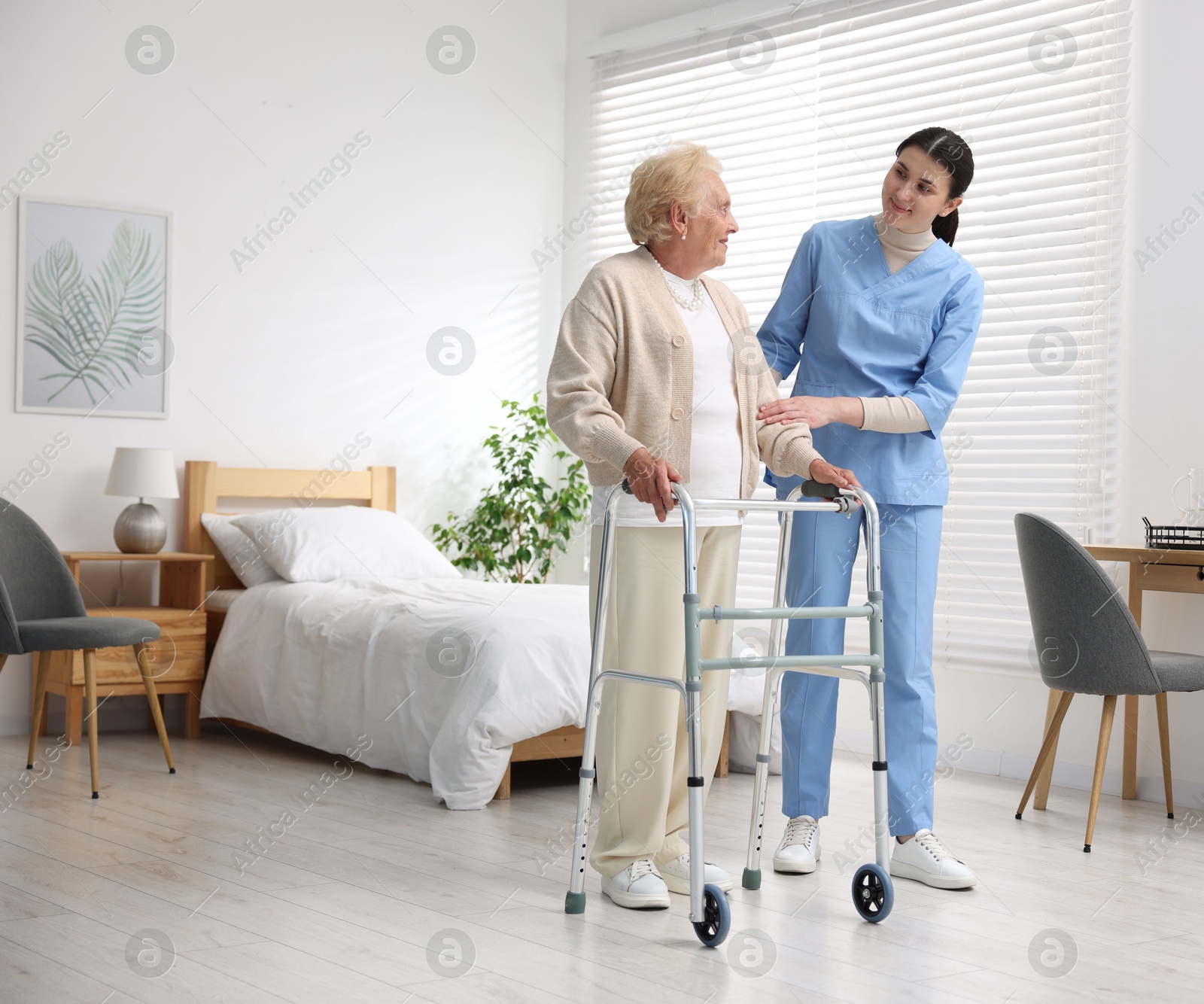 Nurse assisting senior woman with walking frame indoors. Home health care service Photo of Nurse assisting senior woman with walking frame indoors. Home health care service