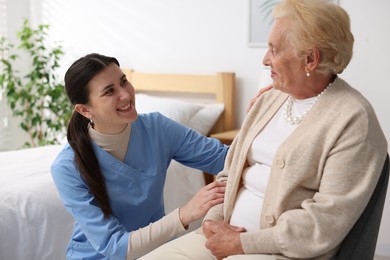 Photo of Nurse assisting senior woman indoors. Home health care service