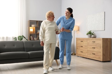 Photo of Nurse assisting senior woman indoors. Home health care service