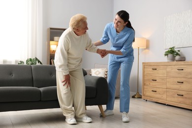 Photo of Nurse assisting senior woman indoors. Home health care service