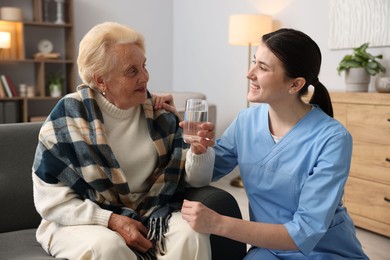 Photo of Nurse assisting senior woman indoors. Home health care service