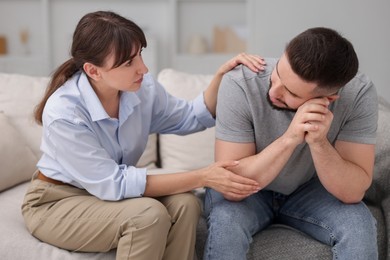 Photo of Psychologist supporting patient during therapy session on sofa in office