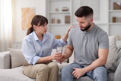 Photo of Psychologist supporting patient during therapy session on sofa in office