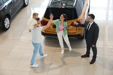 Photo of Salesman giving car key to happy family in salon