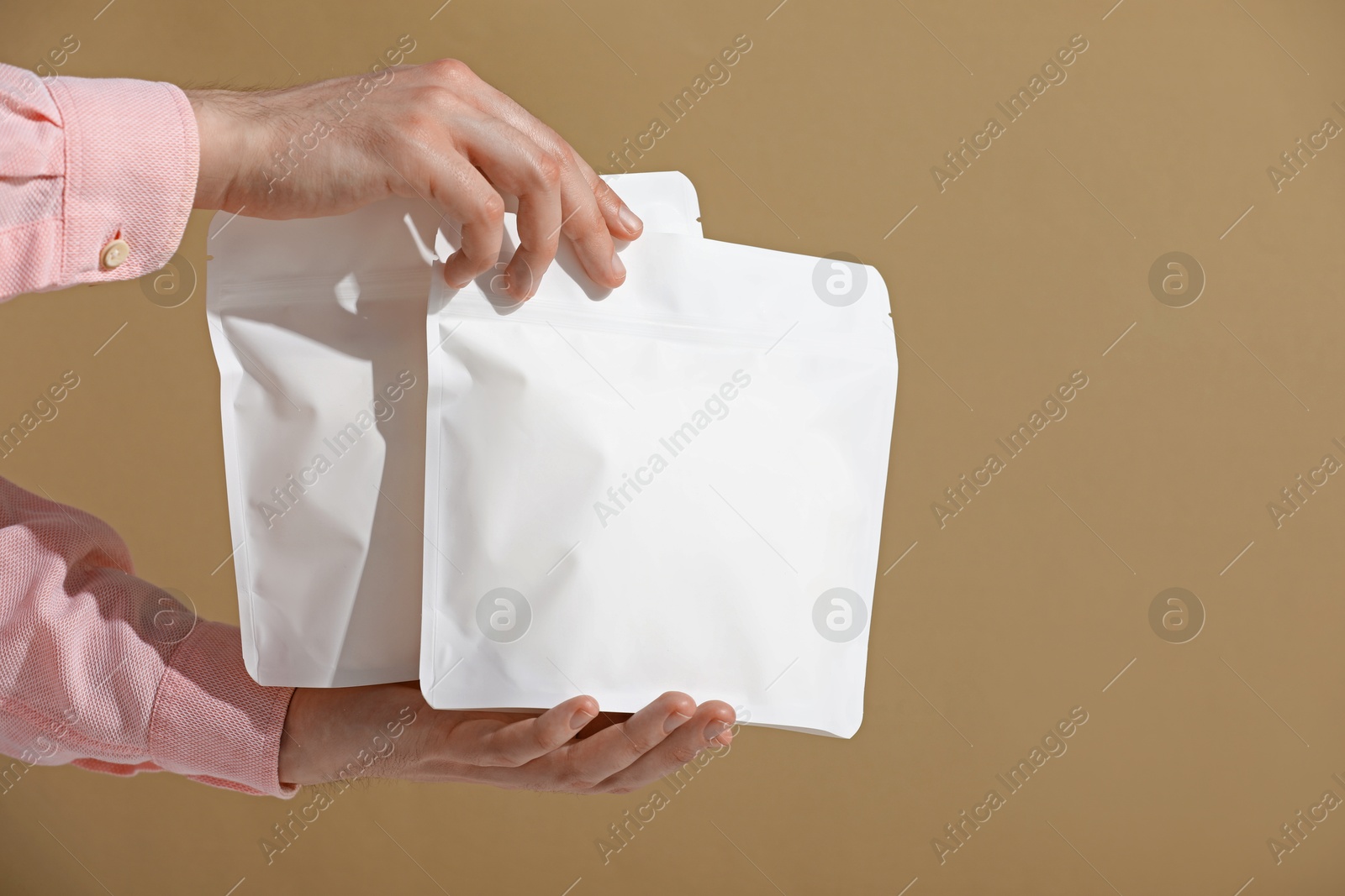 Woman holding blank zipper stand-up pouches on light brown background, closeup. Space for text Photo of Woman holding blank zipper stand-up pouches on light brown background, closeup. Space for text