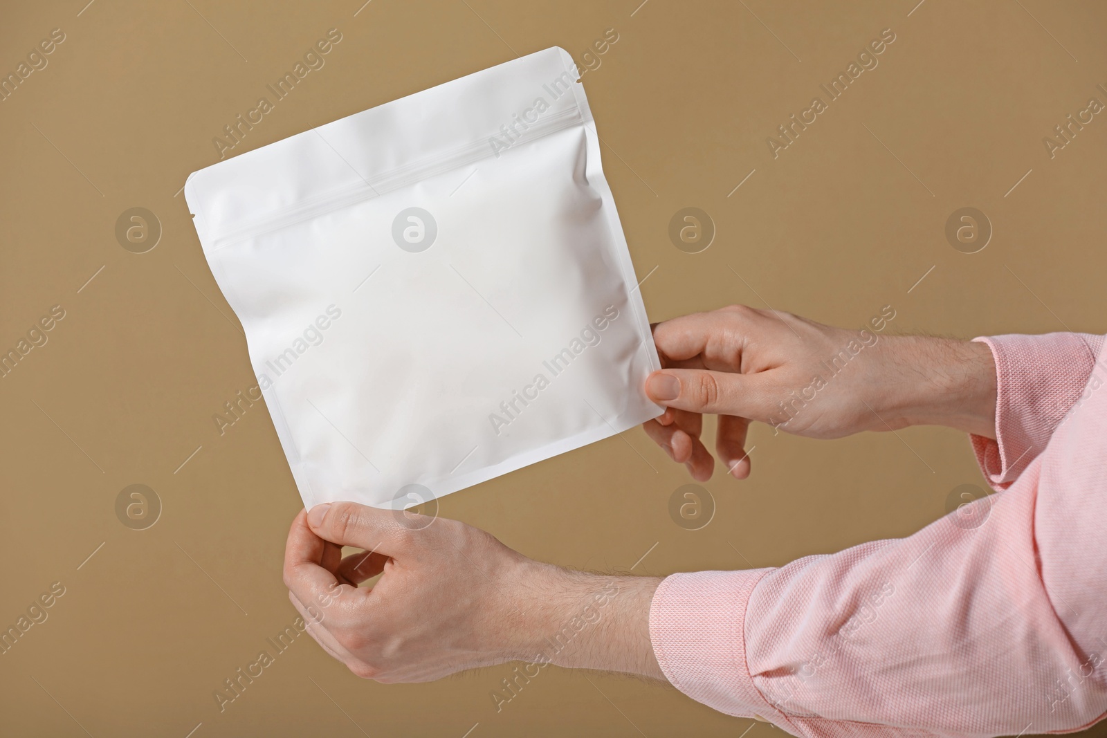 Woman holding blank zipper stand-up pouch on light brown background, closeup. Space for text Photo of Woman holding blank zipper stand-up pouch on light brown background, closeup. Space for text