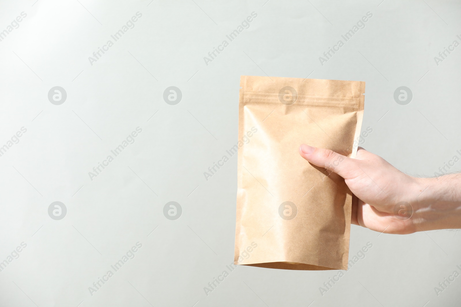 Woman holding blank zipper stand-up pouch on light grey background, closeup. Space for text Photo of Woman holding blank zipper stand-up pouch on light grey background, closeup. Space for text