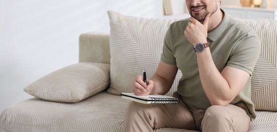 Photo of Professional psychologist with notebook on sofa in office, closeup. Space for text