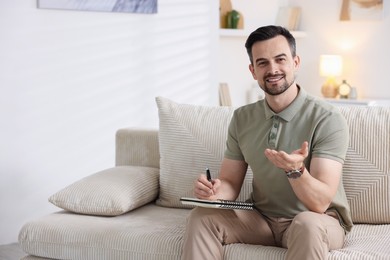 Photo of Professional psychologist with notebook on sofa in office. Space for text