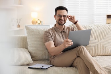 Photo of Professional psychologist having online consultation with his client via laptop on sofa indoors