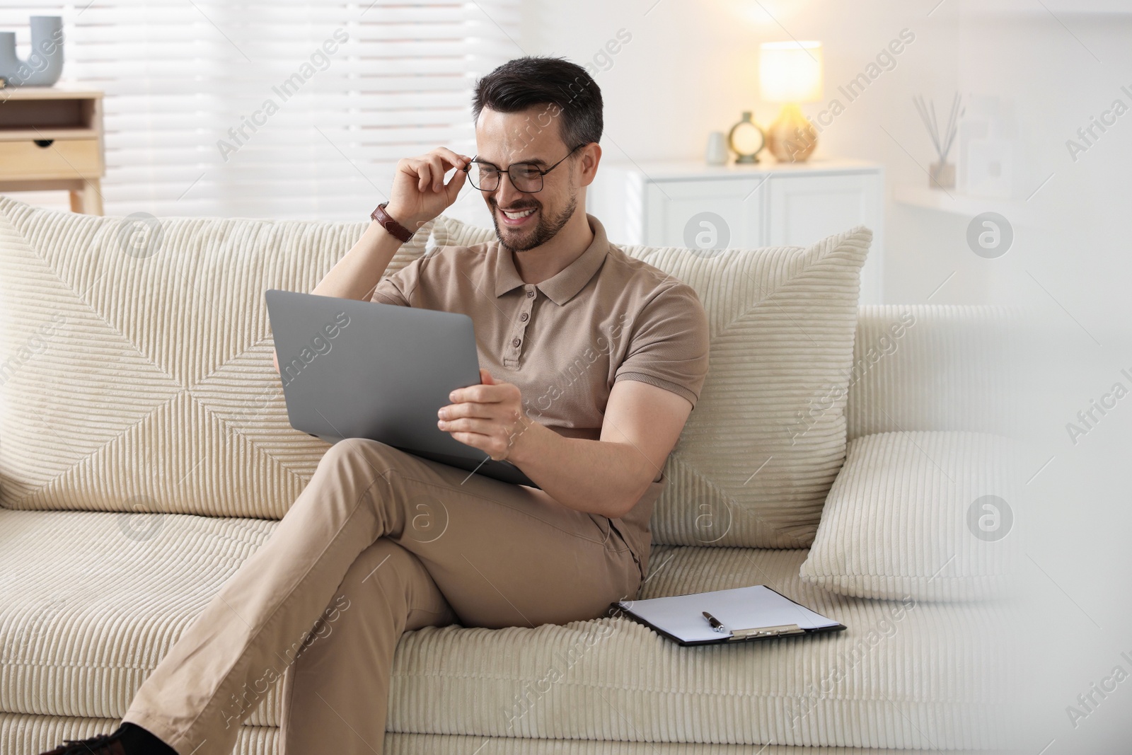 Photo of Professional psychologist having online consultation with his client via laptop on sofa indoors