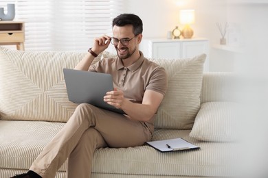 Photo of Professional psychologist having online consultation with his client via laptop on sofa indoors