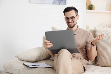 Photo of Professional psychologist having online consultation with his client via laptop on sofa indoors. Space for text