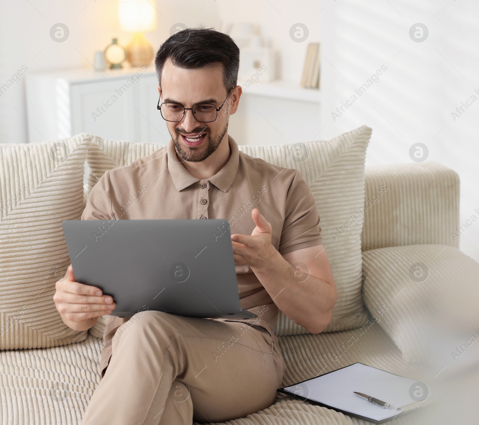Photo of Professional psychologist having online consultation with his client via laptop on sofa indoors