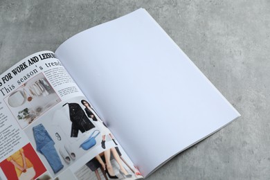 Photo of Open magazine on grey table, above view. Mockup for design