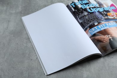 Photo of Open magazine on grey table, above view. Mockup for design