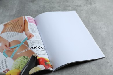 Photo of Open magazine on grey table, above view. Mockup for design
