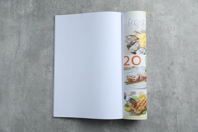 Photo of Open magazine on grey table, top view. Mockup for design