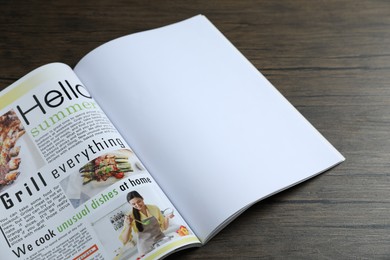 Photo of Open magazine on wooden table, above view. Mockup for design