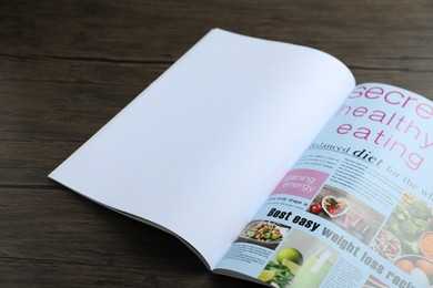 Photo of Open magazine on wooden table, above view. Mockup for design