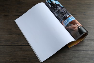 Photo of Open magazine on wooden table, above view. Mockup for design