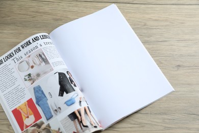 Photo of Open magazine on wooden table, above view. Mockup for design