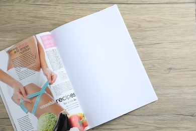 Photo of Open magazine on wooden table, top view. Mockup for design