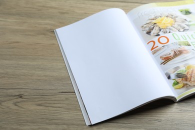 Photo of Open magazine on wooden table, above view. Mockup for design
