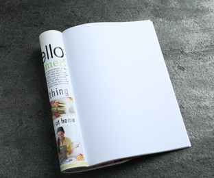 Photo of Open magazine on grey table, above view. Mockup for design