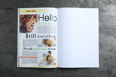 Photo of Open magazine on grey table, top view. Mockup for design