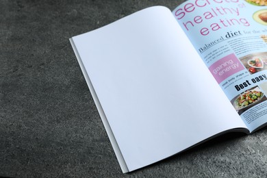 Photo of Open magazine on grey table, above view. Mockup for design