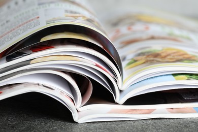 Photo of Different open magazines on grey table, closeup