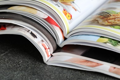 Photo of Different open magazines on grey table, closeup