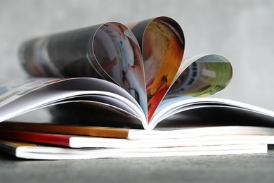 Photo of Stack of different magazines on grey table, closeup