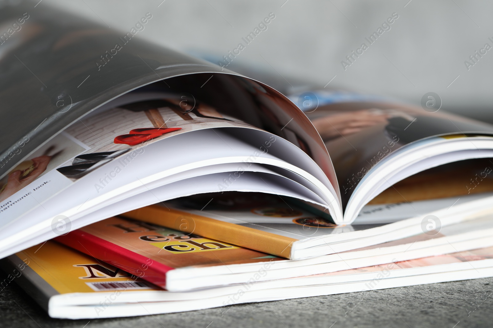 Stack of different magazines on grey table, closeup Photo of Stack of different magazines on grey table, closeup