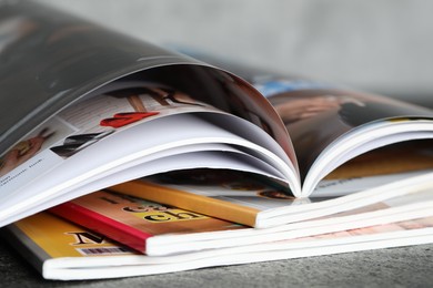 Photo of Stack of different magazines on grey table, closeup