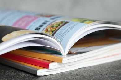Photo of Stack of different magazines on grey table, closeup