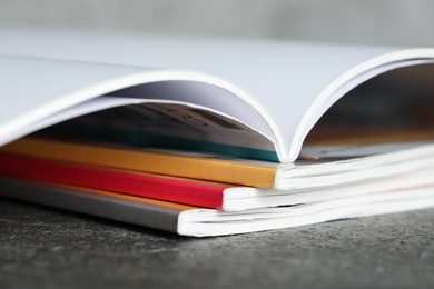 Photo of Stack of different magazines on grey table, closeup