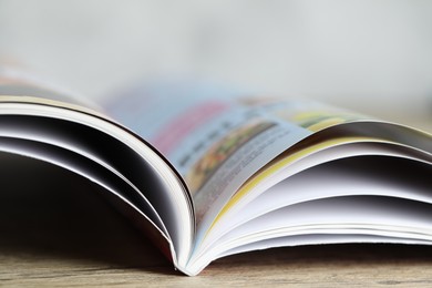 Photo of One open magazine on wooden table, closeup