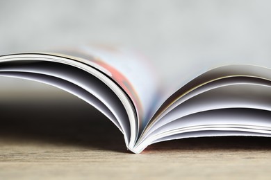 Photo of One open magazine on wooden table, closeup