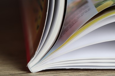 Photo of One open magazine on wooden table, closeup