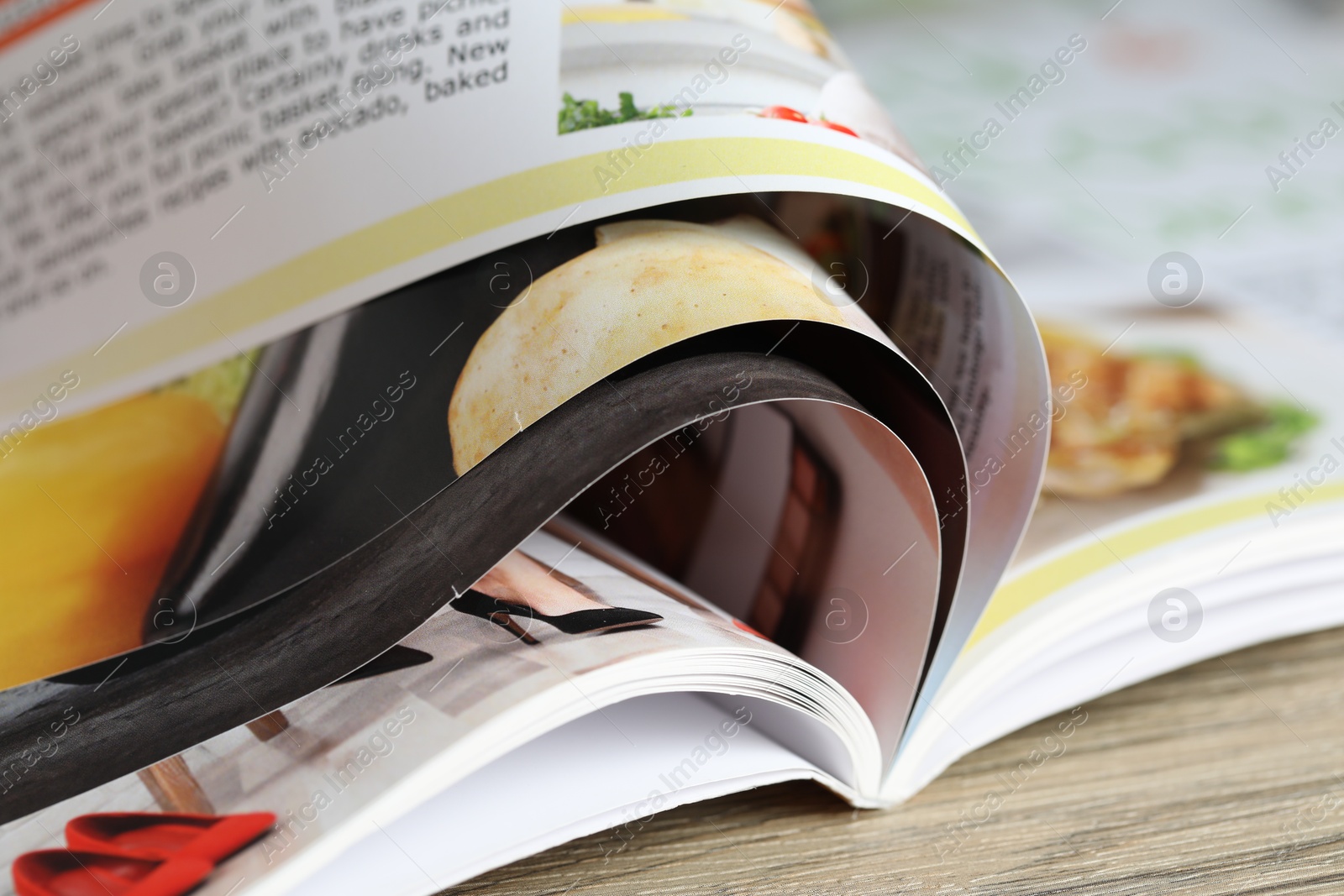 One open magazine on wooden table, closeup Photo of One open magazine on wooden table, closeup