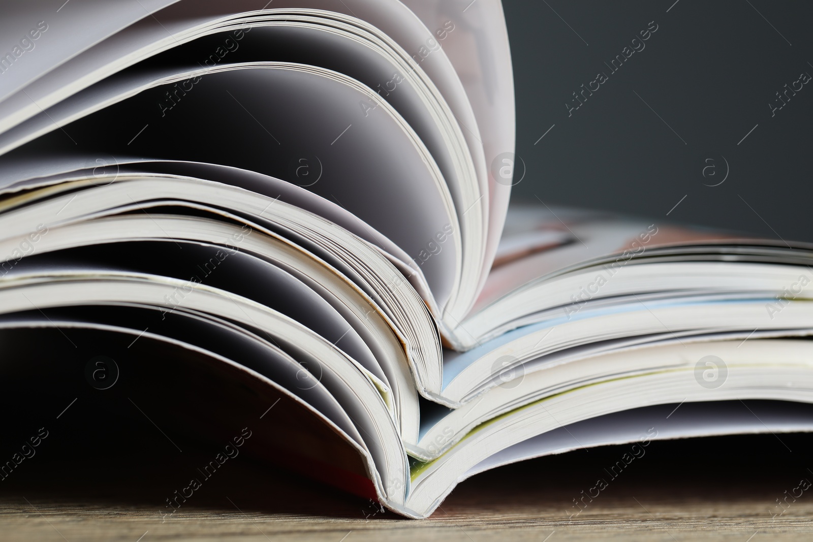 Different open magazines on wooden table, closeup Photo of Different open magazines on wooden table, closeup