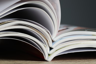 Photo of Different open magazines on wooden table, closeup