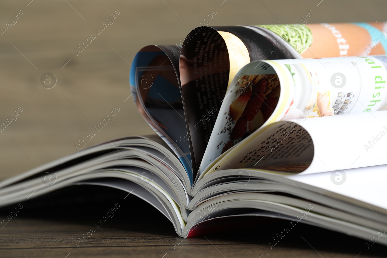 Different open magazines on wooden table, closeup Photo of Different open magazines on wooden table, closeup