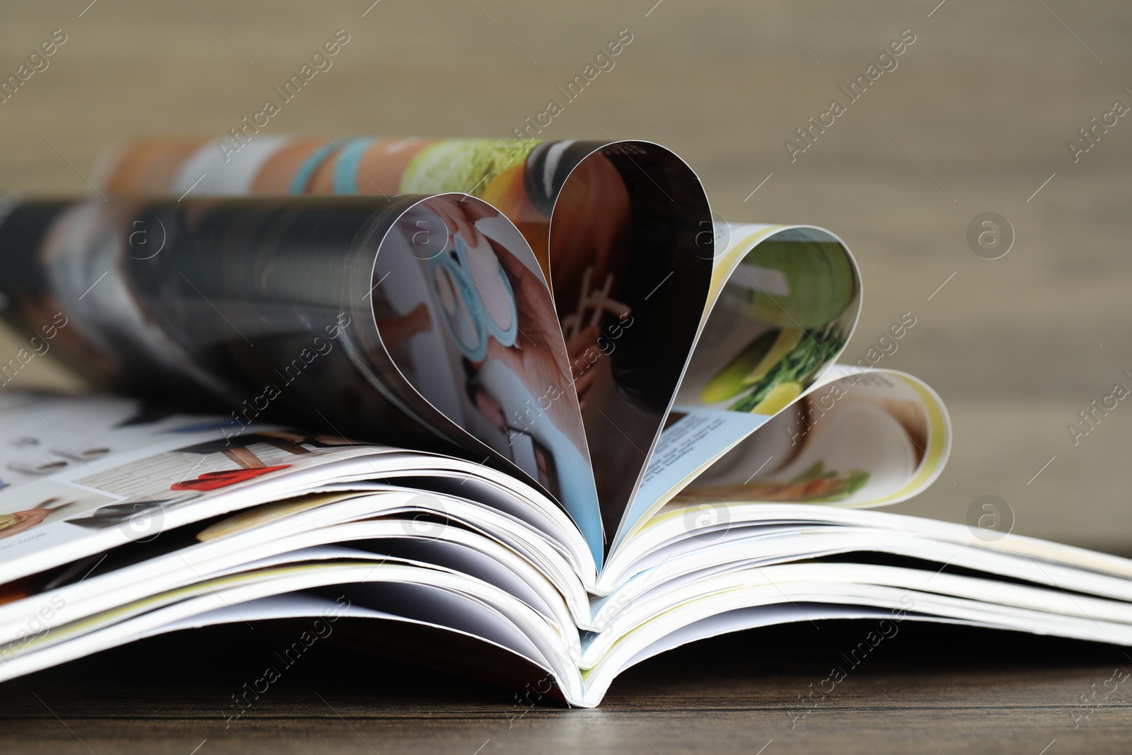 Different open magazines on wooden table, closeup Photo of Different open magazines on wooden table, closeup